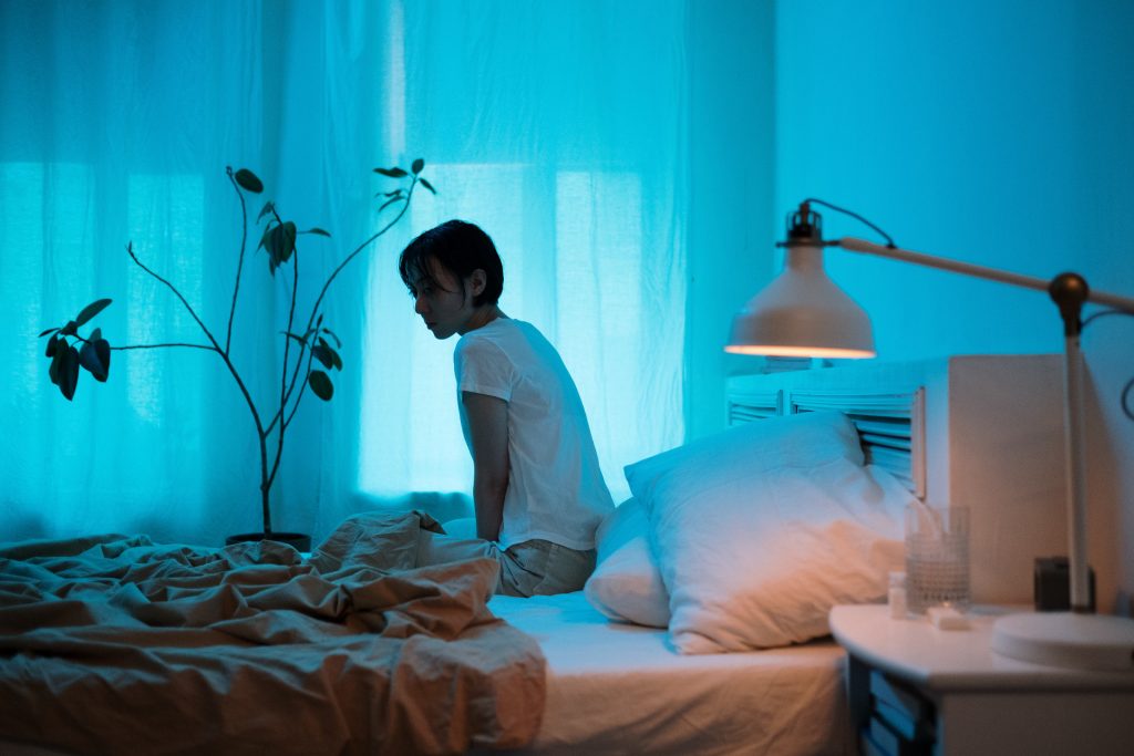 Woman sitting alone on a bed - blue feeling