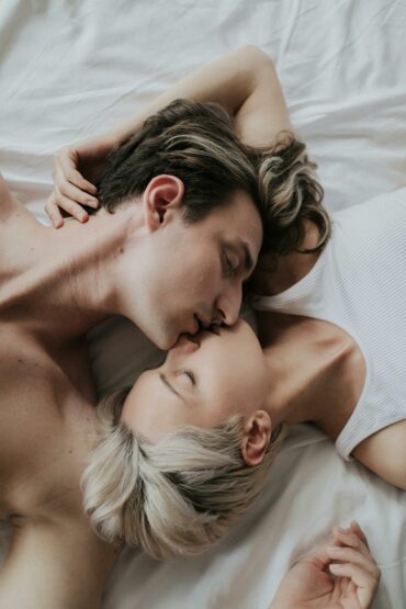 Mann und Frau, die sich im Bett küssen.