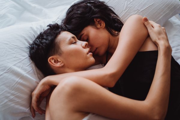 Two women hugging each other in bed.